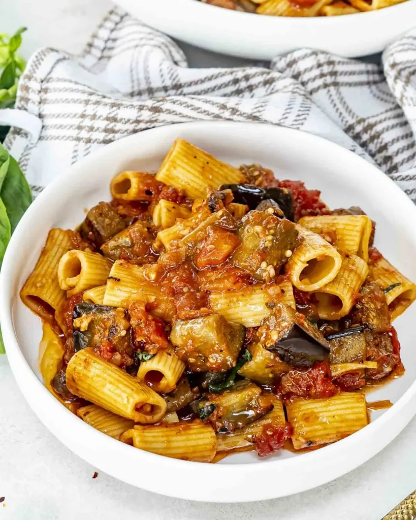 Assiette de pâtes à la Norma garnies d'aubergines dorées, sauce tomate, pecorino râpé et basilic frais Assiette de pâtes à la Norma garnies d'aubergines dorées, sauce tomate, pecorino râpé et basilic frais